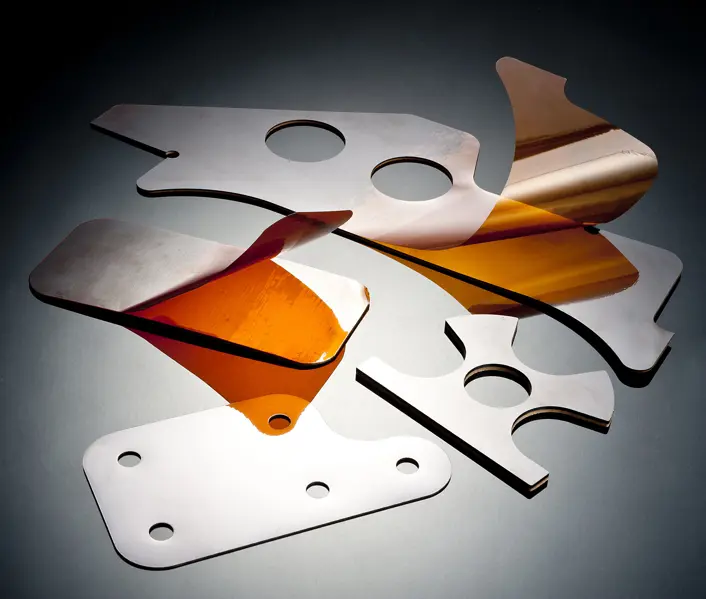Precision-machined aerospace shims in metallic and amber materials, showing a range of custom shapes and sizes manufactured by Avantus Aerospace.