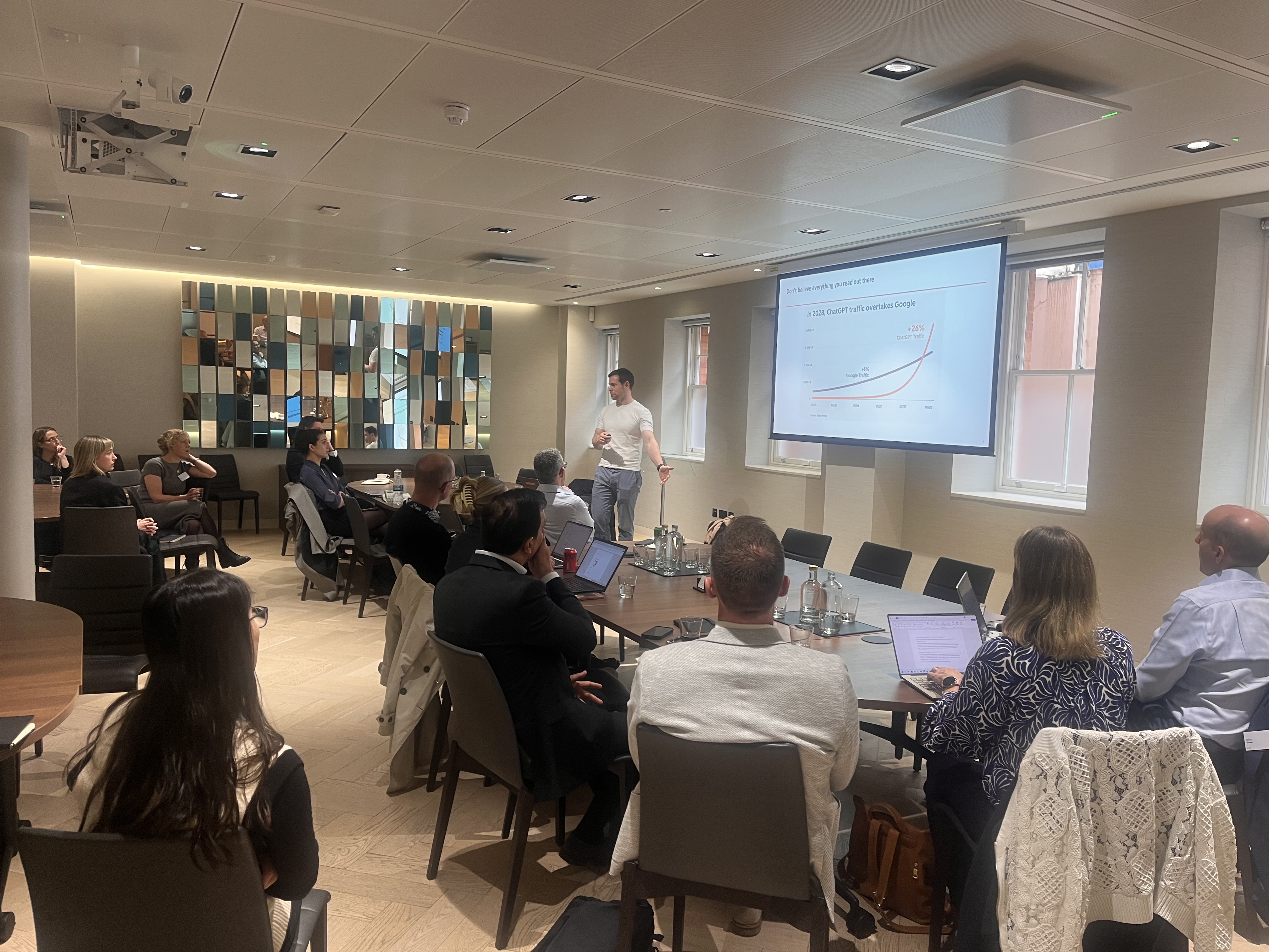 Speaker presenting at the Inflexion Marketing Exchange 2026 to attendees seated around a boardroom table.