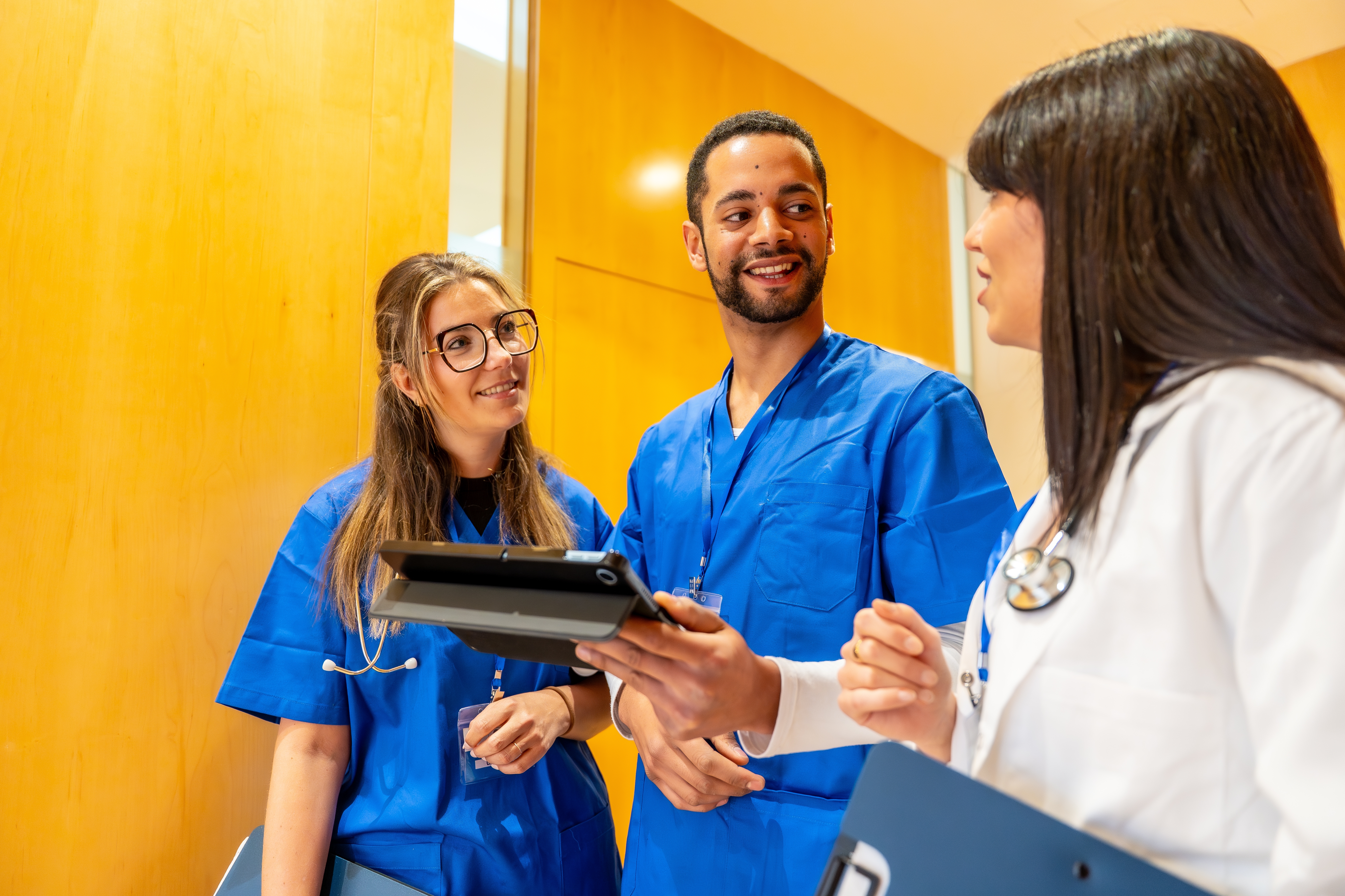 Medical team of diverse healthcare workers standing together, reviewing patient data 