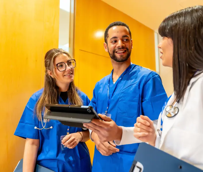 Medical team of diverse healthcare workers standing together, reviewing patient data 